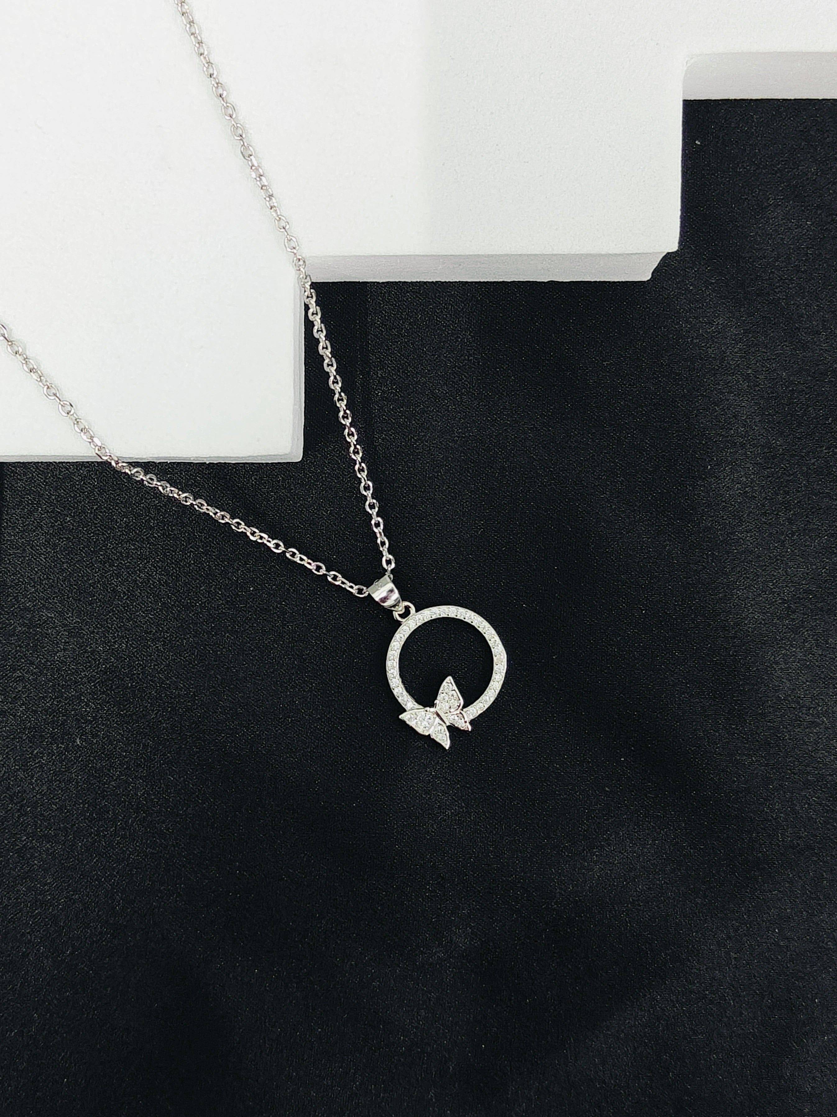 Silver necklace with a butterfly pendant on a black stand